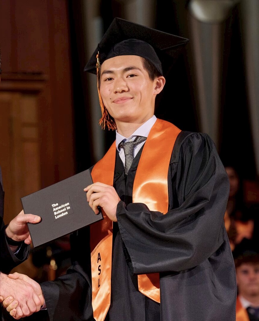 Markus holding diploma at graduation